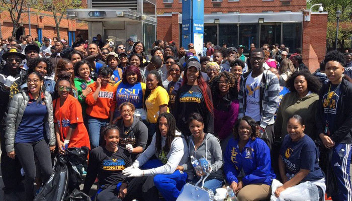 A large group of Black male and female students posing in front of a Coppin State University building